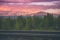 铁轨上松树与山脉间的戏剧性日出