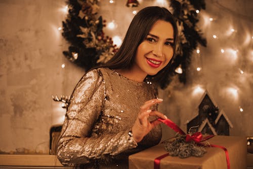 Woman in Brown Long Sleeve Dress Holding a Gift