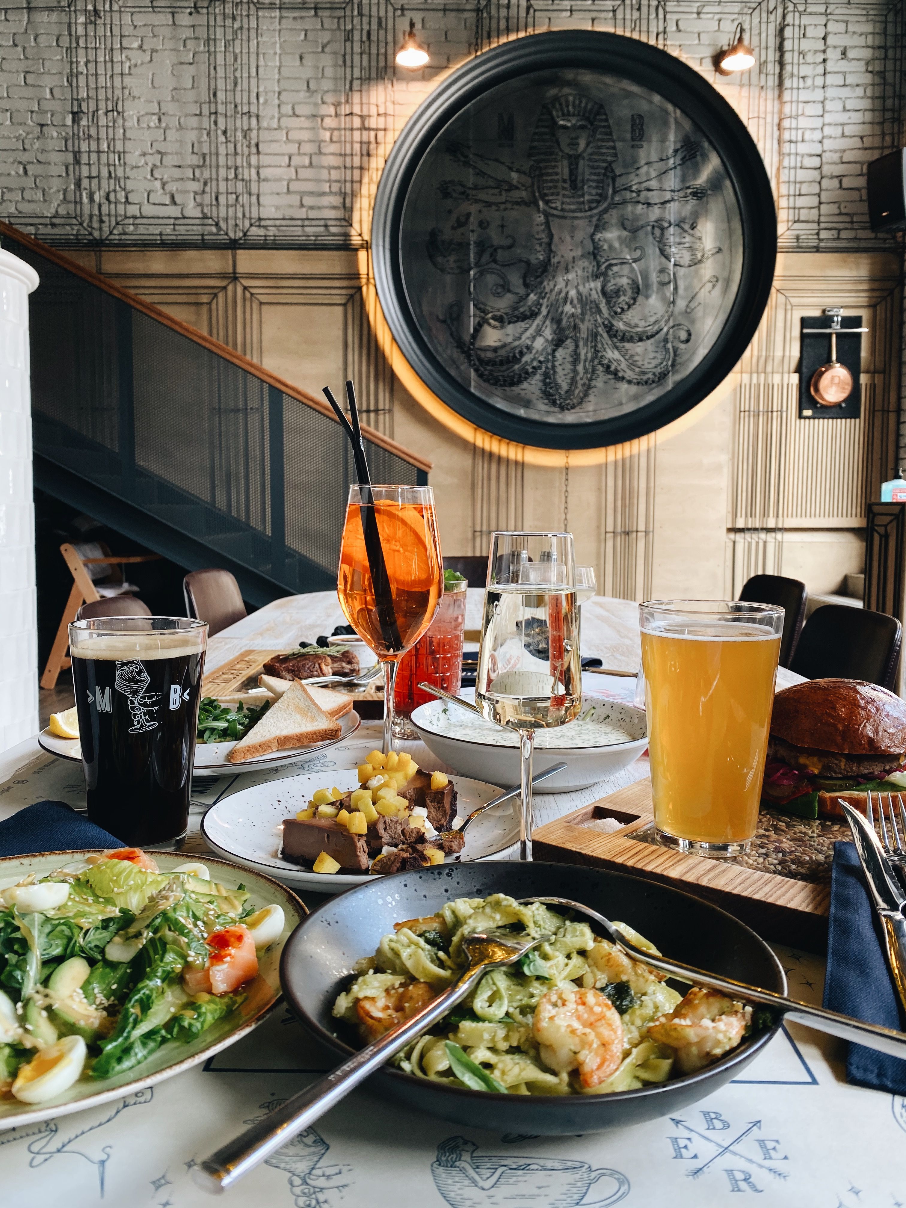 A luxurious restaurant setup featuring seafood pasta, cocktails, and rustic decor.
