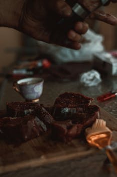 Close-up of raw meat slices on a cutting board with culinary tools.