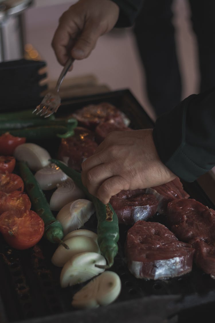 A Person Holding Stainless Steel Fork While Grilling