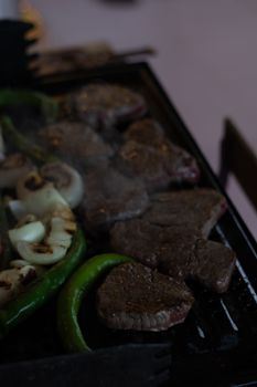 Juicy steaks and vegetables sizzling on an outdoor barbecue grill.
