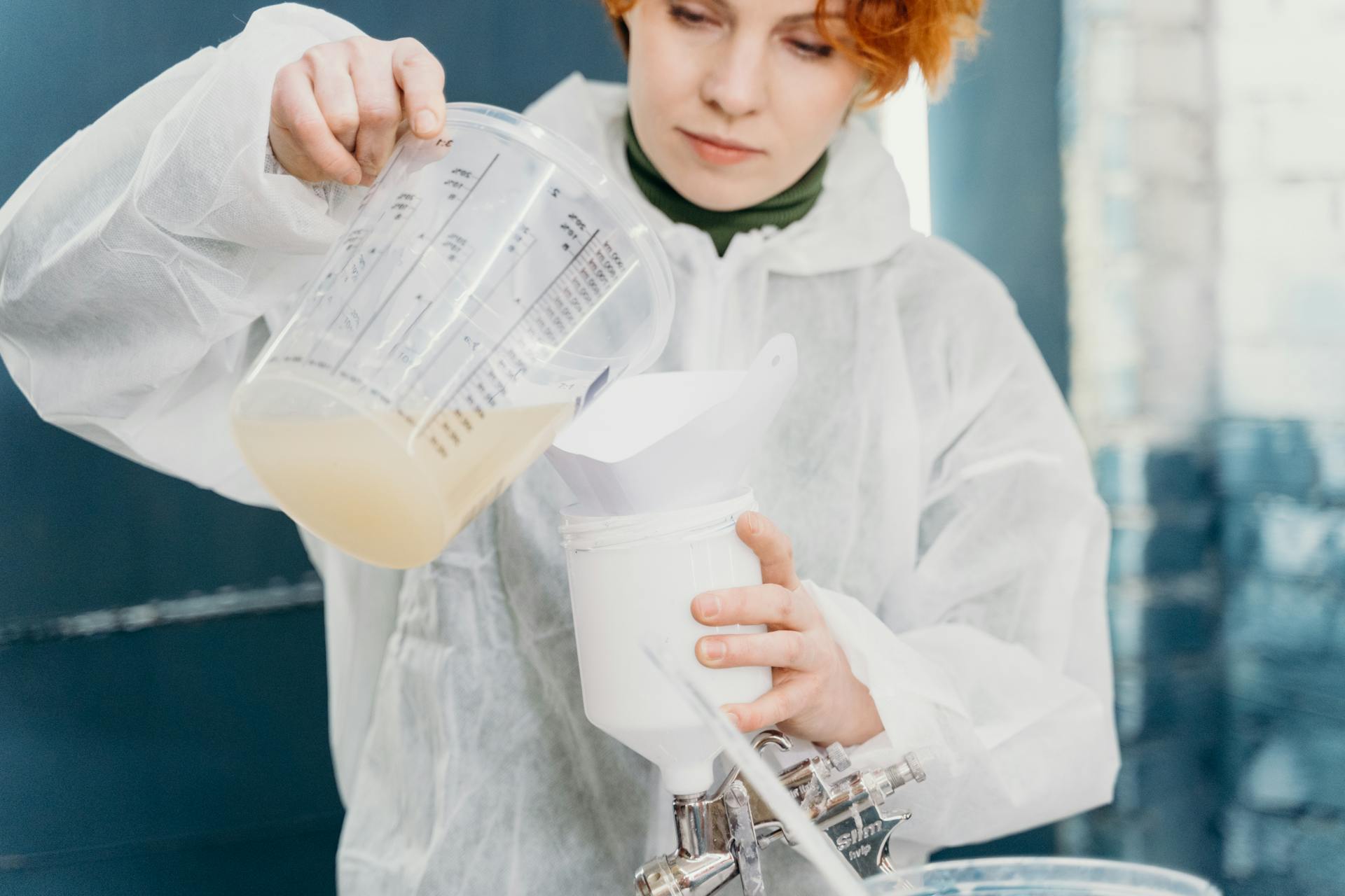 A Woman Pouring a Liquid from a Glass Container