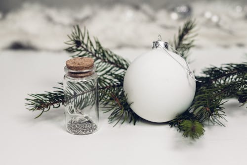 Selective Focus Photography of White Christmas Bauble Beside Bottle With Cork Lid