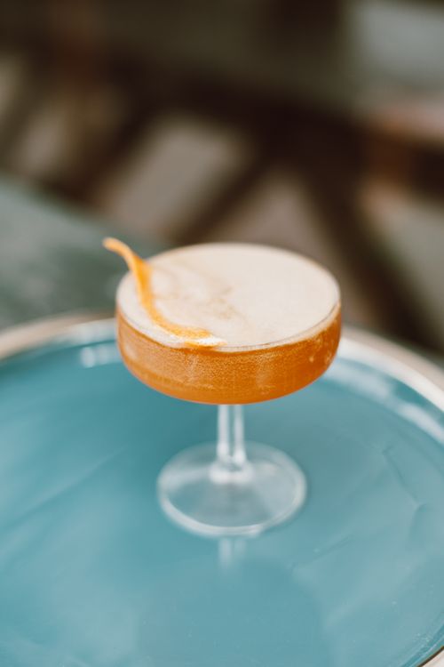 Free Refreshing cocktail with orange twist in a stylish coupe glass on a blue surface. Stock Photo