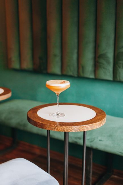 Sophisticated cocktail elegantly placed on a modern wooden table in a stylish lounge setting.