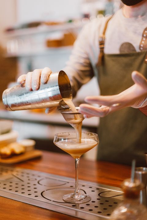 Mocktail Masterclass: 8 Café-Quality Drinks to Make at Home 2 Professional bartender carefully straining a mocktail into a glass at a bar counter