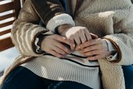 A close-up of a couple holding hands, dressed in warm winter clothing, representing affection and intimacy.