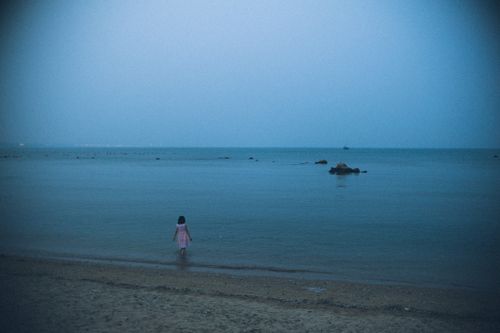Free A young girl stands by the sea at Qinhuangdao, Hebei, China during twilight. Stock Photo
