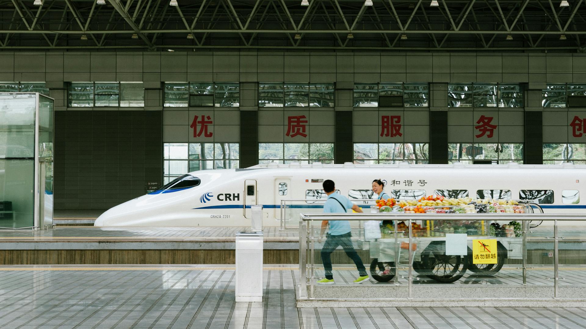 Chinese high-speed train at Yichang station with passengers and vendors.