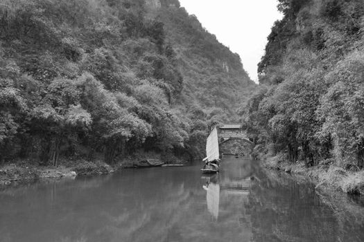 Peaceful black and white scenery of a traditional boat on a calm river in Yichang, China.
