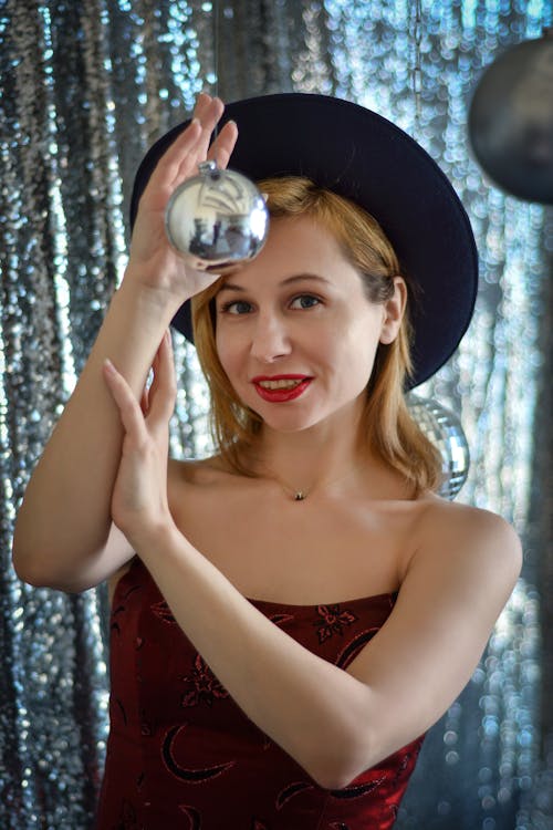 Positive woman in hat touching Christmas bauble