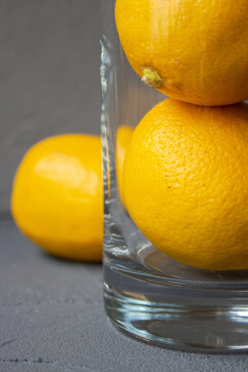 Free Glass vase with fresh whole lemons in gray studio Stock Photo