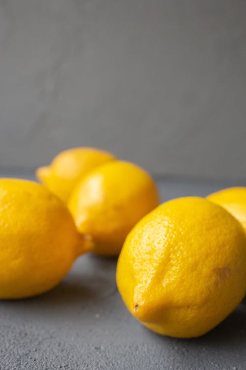 Free Pile of fresh healthy whole lemons scattered on gray surface in studio in daylight Stock Photo