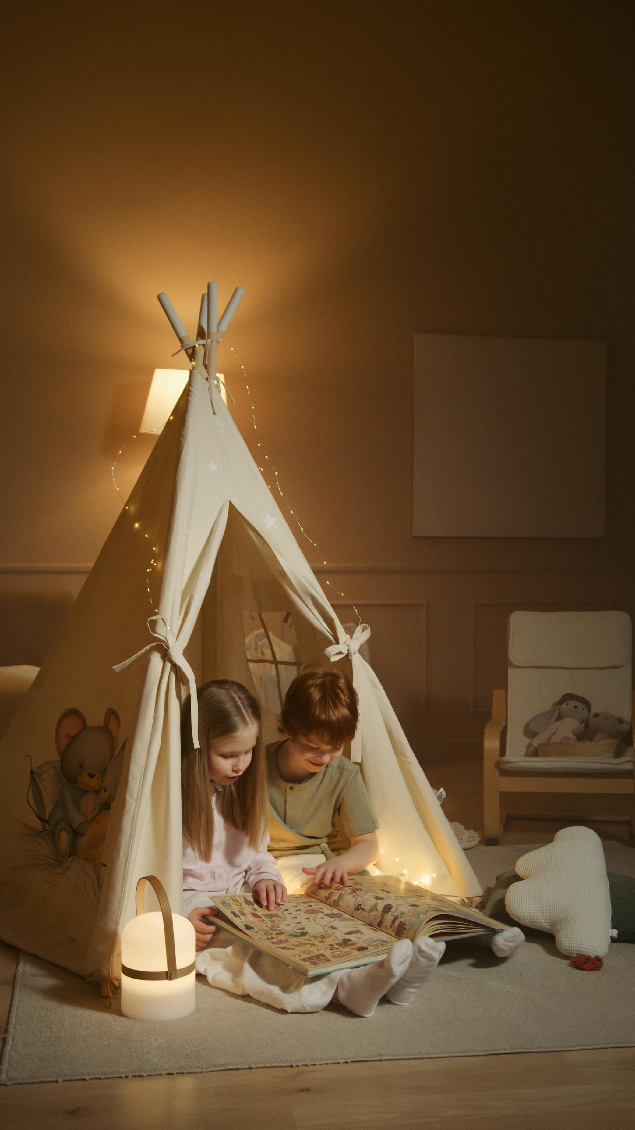 kids reading a book in a tent