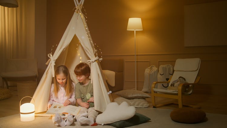 Children Reading A Book While Inside An Indoor Tent