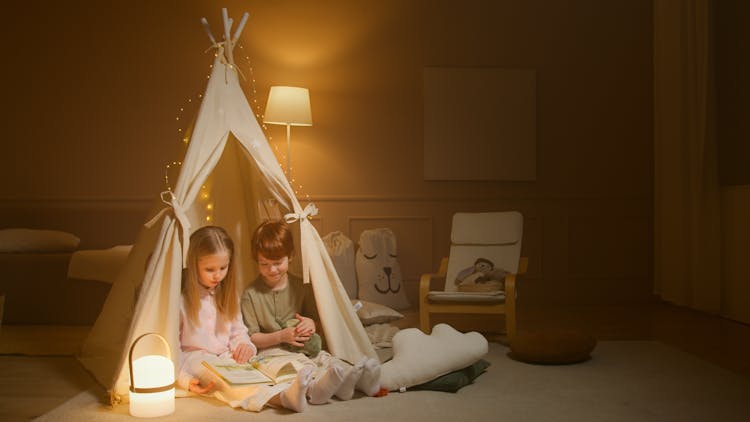 
Children Reading A Book While Inside An Indoor Tent