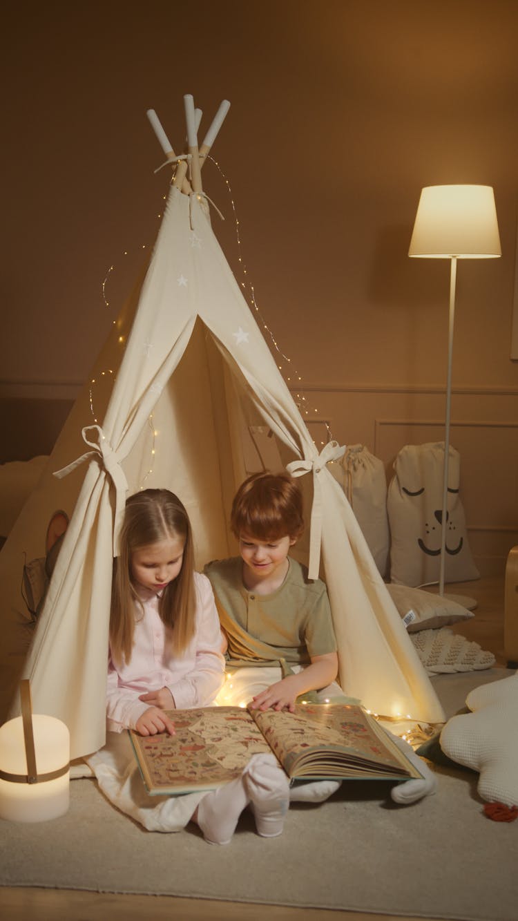 Children Reading A Book While Inside An Indoor Tent