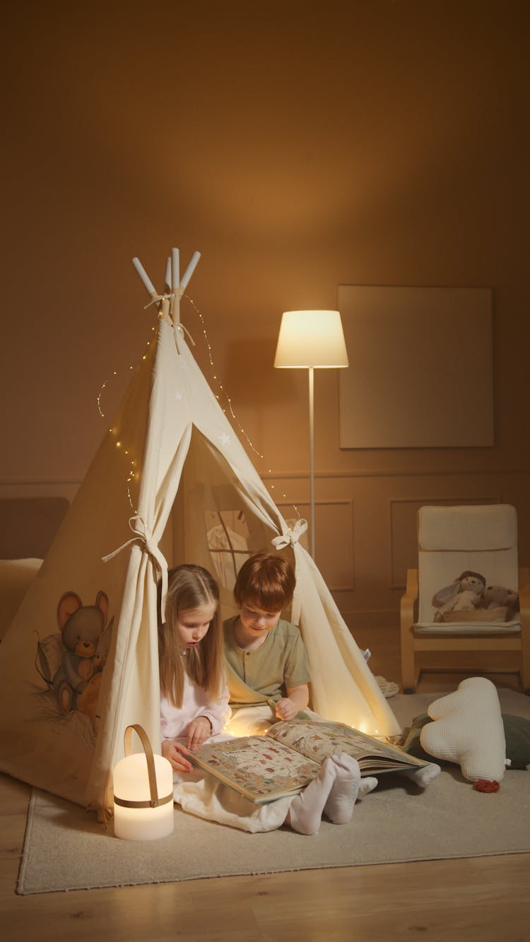 Children Reading A Book While Inside An Indoor Tent