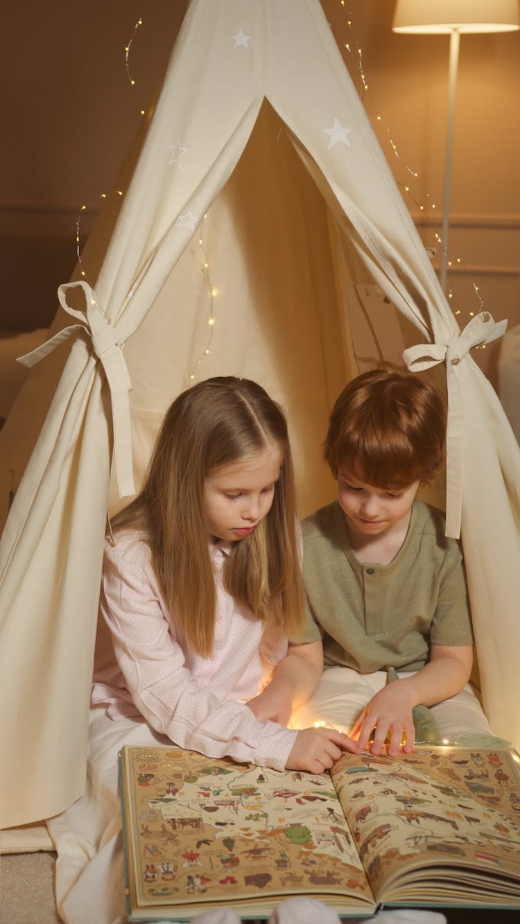 Children Reading A Book While Inside An Indoor Tent