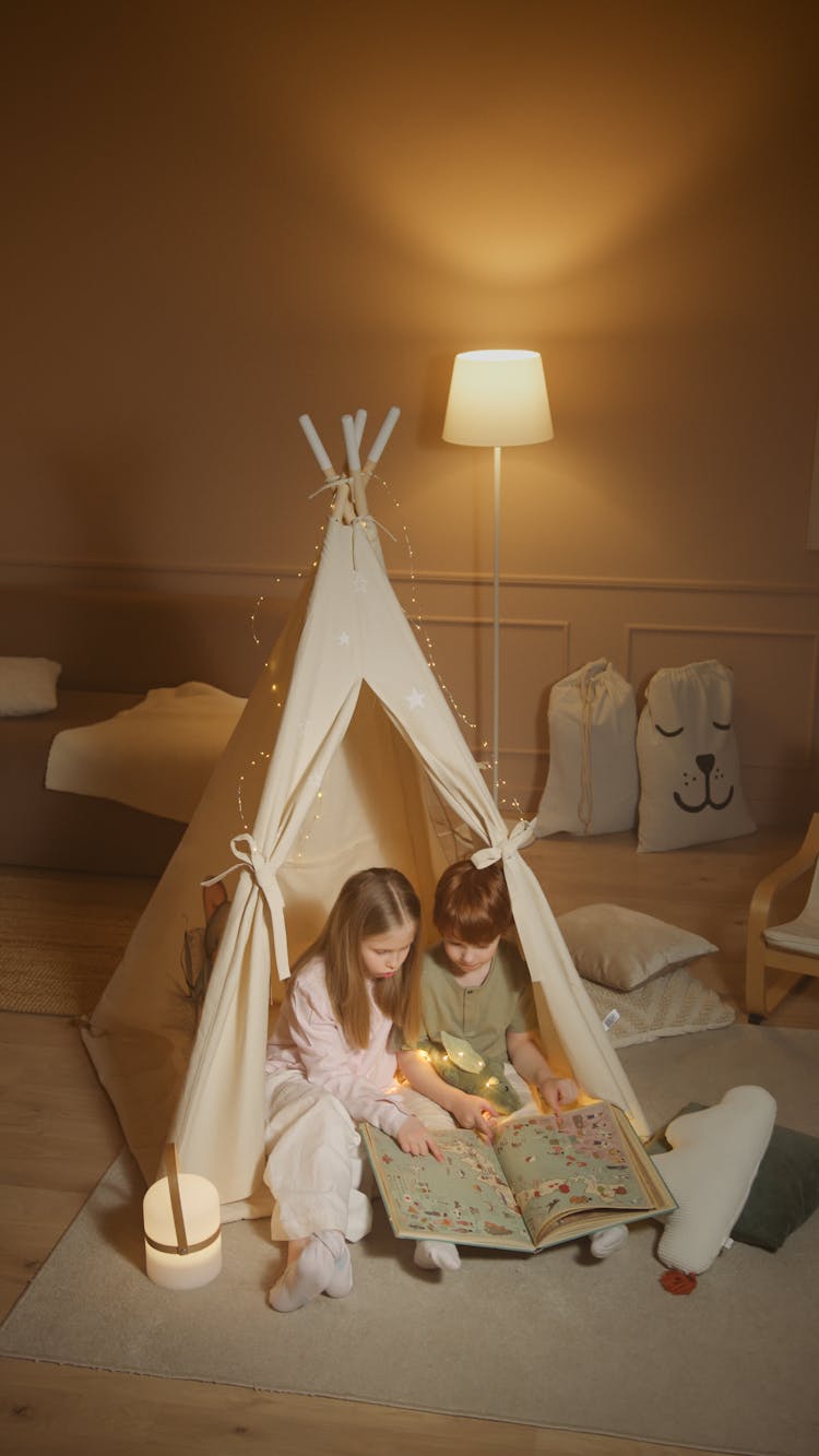 Children Reading A Book While Inside An Indoor Tent