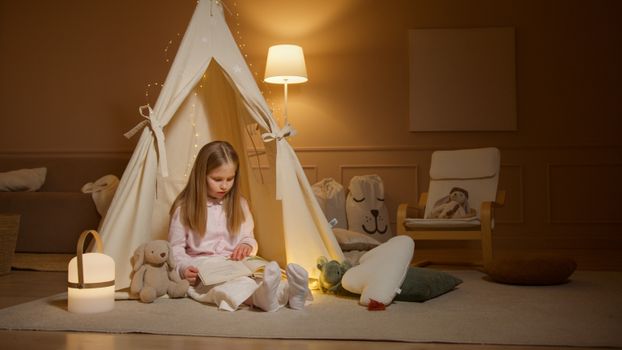 Photo of a Girl Reading a Book Near a Tent