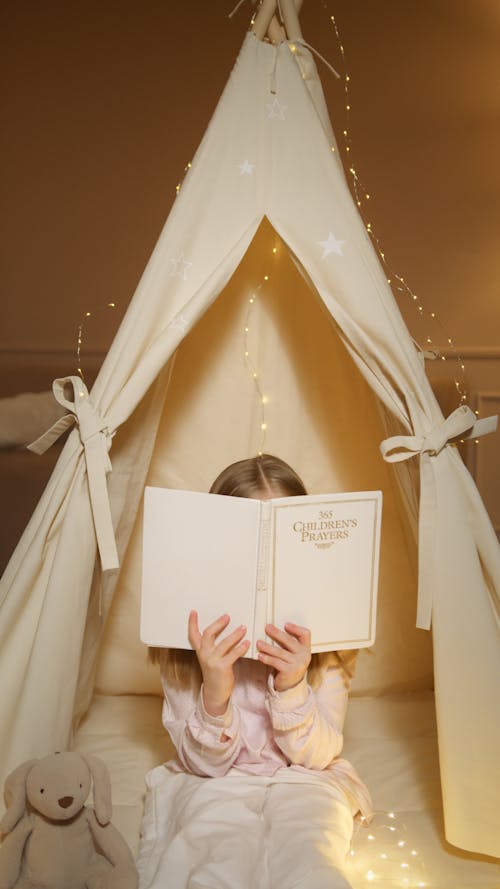 Free Photo of a Girl Reading a Book Near a Wigwam Tent Stock Photo