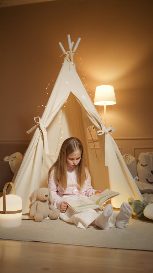 Free Photo of a Child Reading a Book Beside a Stuffed Toy Stock Photo