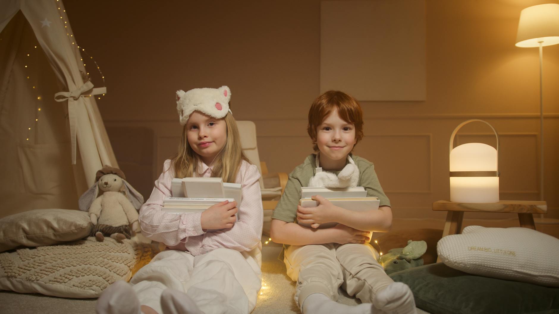 Children in pajamas holding books, ready for a cozy bedtime story indoors.