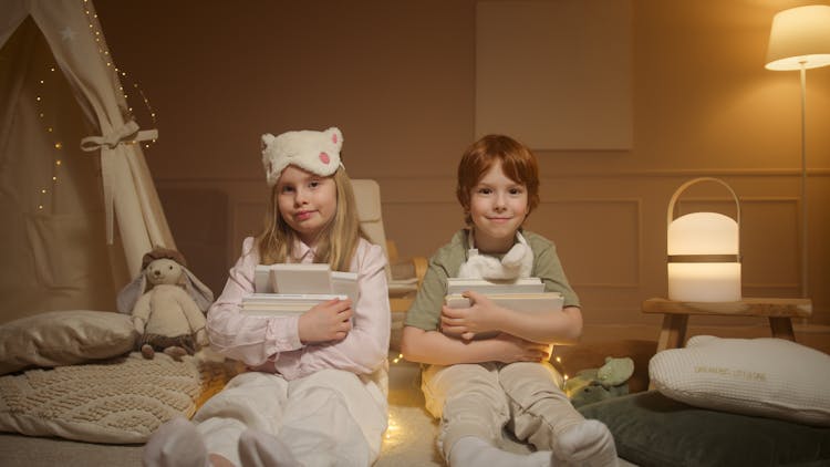 A Girl And A Boy In Pajamas Holding Books