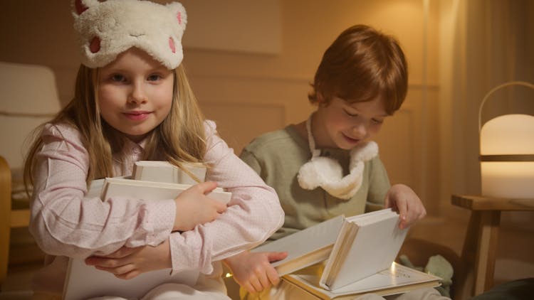 A Girl And A Boy In Pajamas Holding Books
 