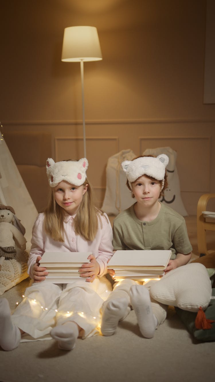 Siblings With Stacks Of Books On Their Laps