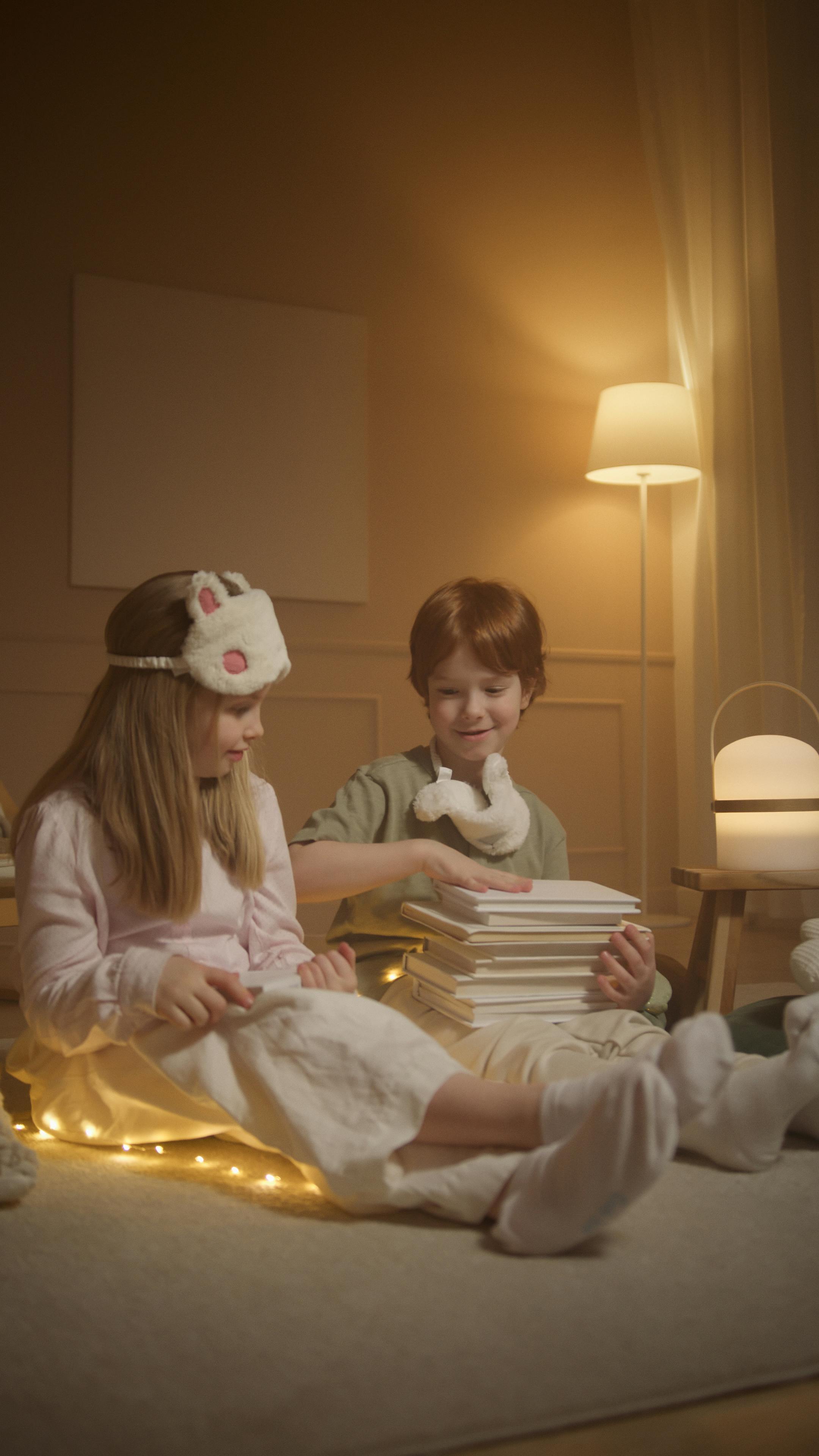 a girl with his brother with a stack of books on his lap