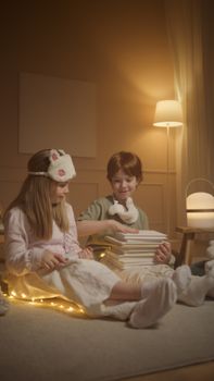 Two children reading books with sleep masks in a cozy, warm-lit room, creating bedtime atmosphere.