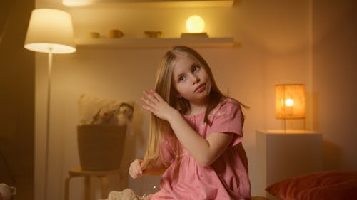 Free A Blonde Pretty Girl in Pink Sleepwear Combing Her Hair Stock Photo