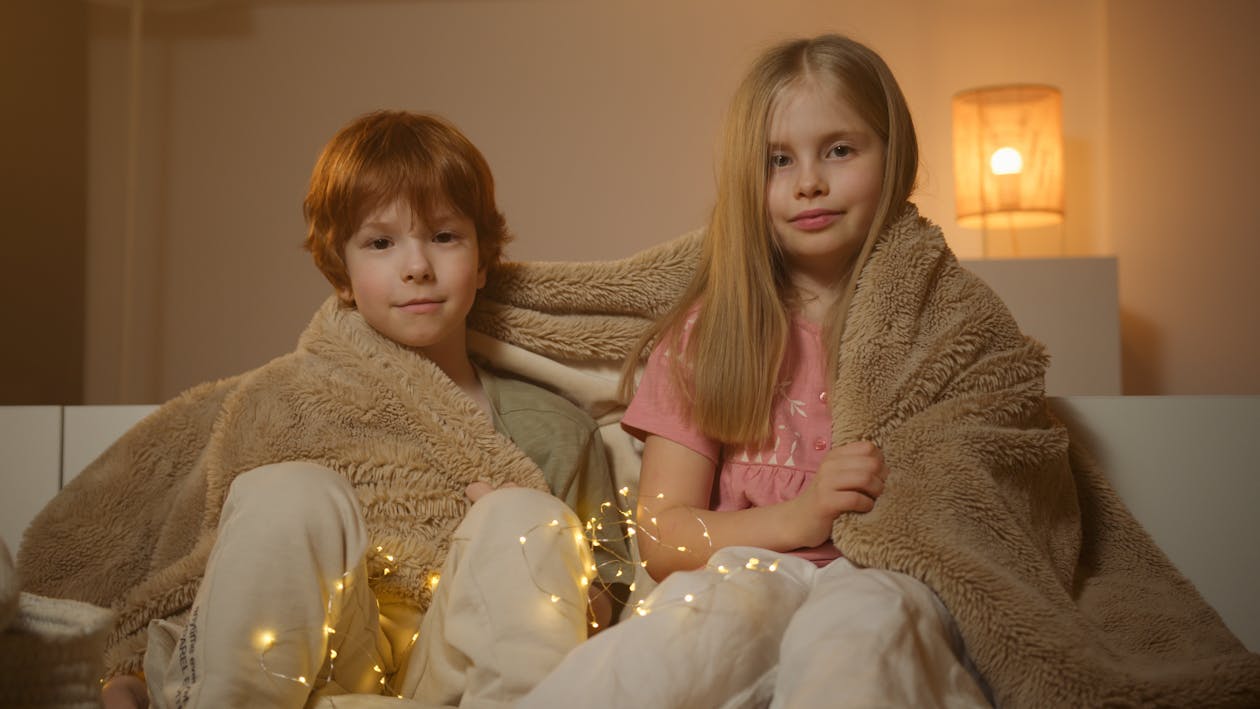 Free Siblings Covered in a Cozy Blanket Stock Photo