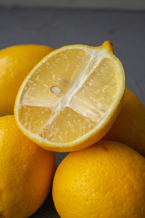 High angle of cut and whole ripe lemons stacked on table against gray background