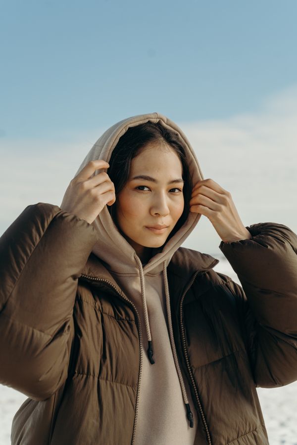 Woman wearing a quilted jacket with beanie and sneakers