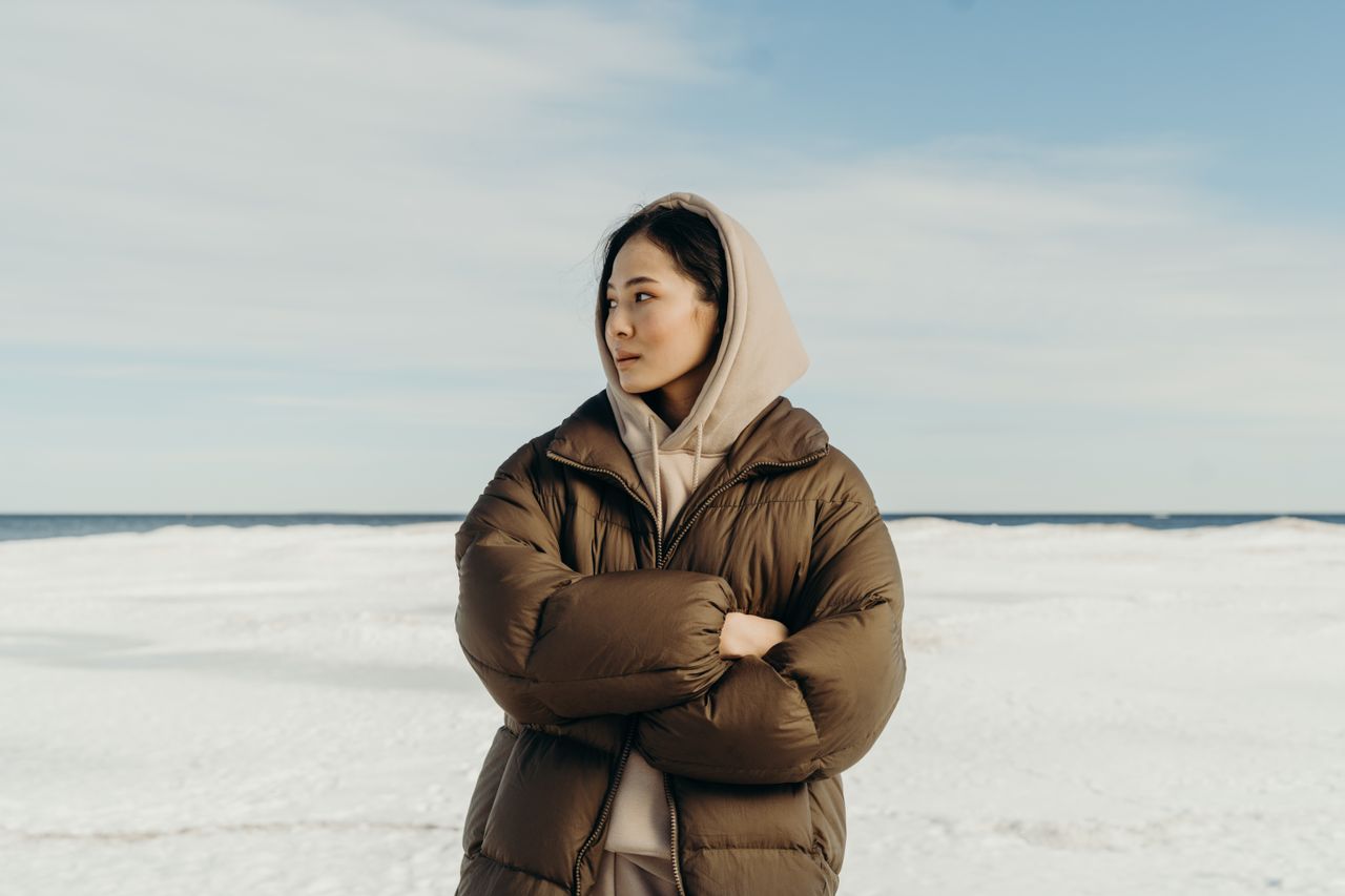 Woman in a brown puffer jacket and hoodie standing on a frozen lake