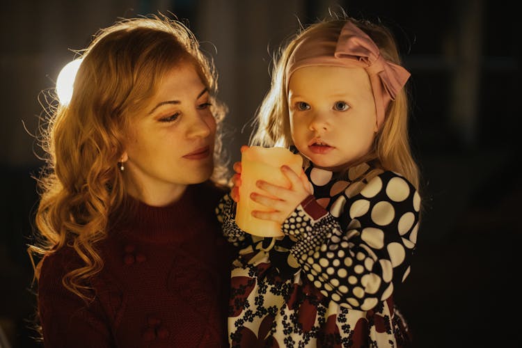 Photograph Of A Girl Holding A Candle Near Her Mother