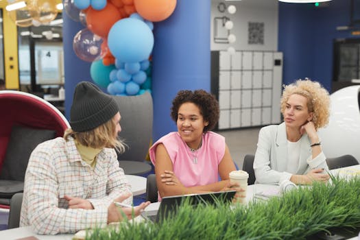 A diverse group of colleagues engaged in discussion at a vibrant, modern office setting.