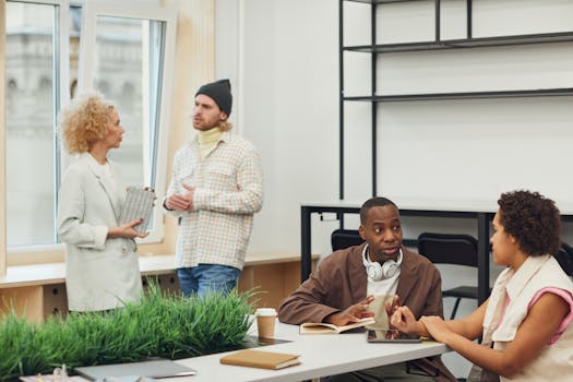 A diverse group of adults discussing project details in a modern office.