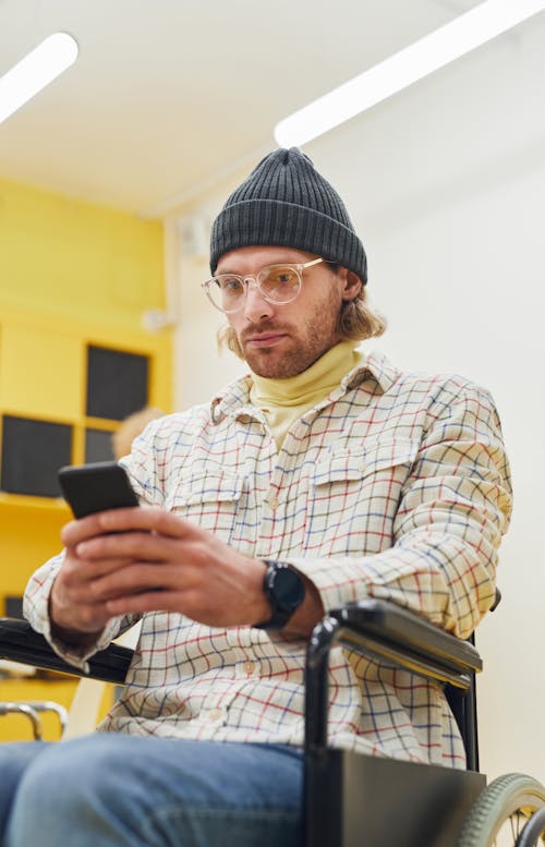 Free Man Sitting in a Wheelchair Looking at His Cellphone Stock Photo