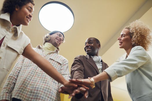 A diverse group of colleagues joyfully engaging in teamwork during an indoor office meeting.