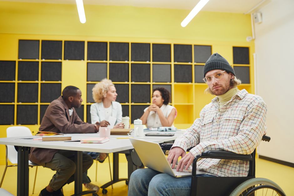 Inclusive office meeting showcasing teamwork and diversity with people collaborating indoors.