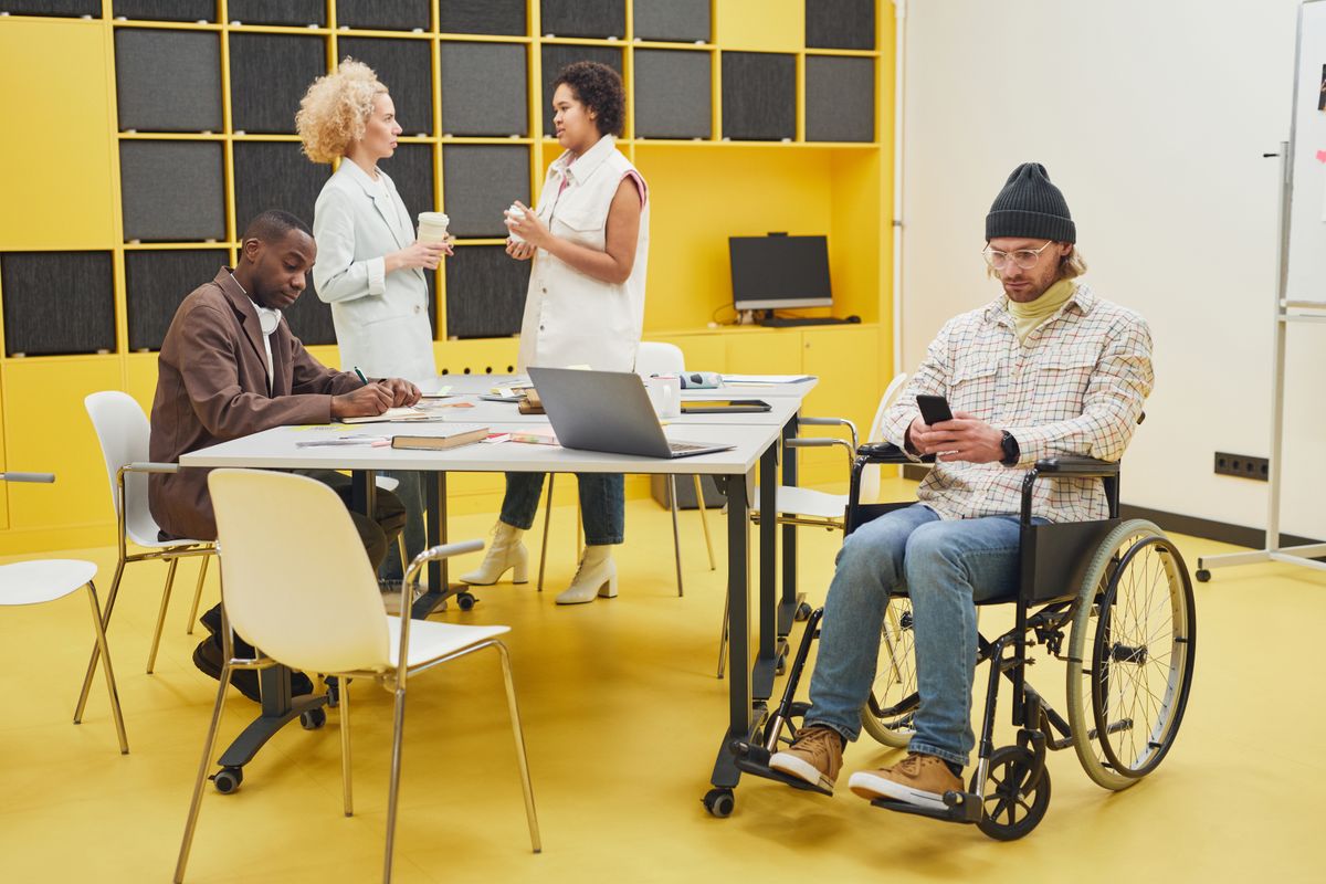 Équipe inclusive en réunion avec un collaborateur en fauteuil roulant