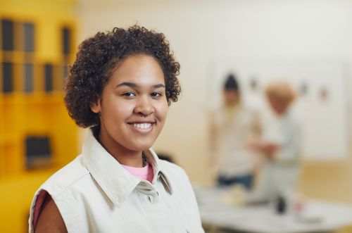 Free Cheerful young woman with curly hair smiling indoors with a blurred background. Stock Photo