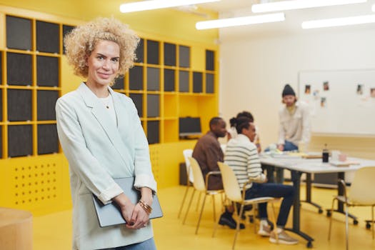 Confident businesswoman standing while a creative team collaborates in a modern office setting.