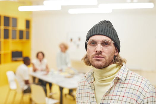 Casual portrait of a man wearing a beanie and glasses in a modern office environment.