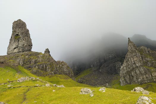 Foggy view of the rugged rock formations and lush greenery of the Old Man of Storr in Scotland.